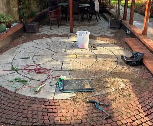 Circular patio covered in moss and dirt before restoration